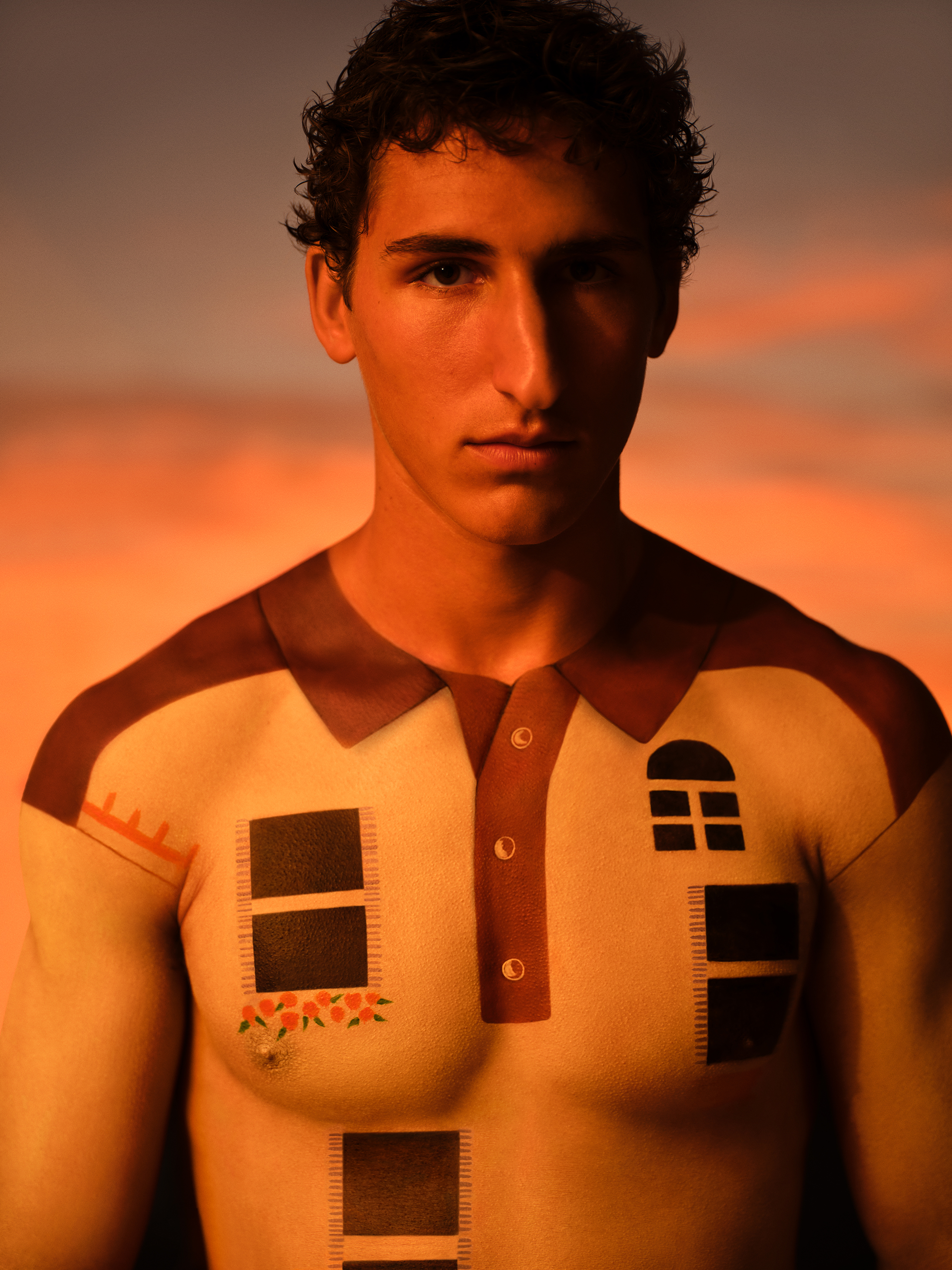 Close up portrait of a model looking at the camera with white body painted top with window graphic details against a warm sunset backdrop
